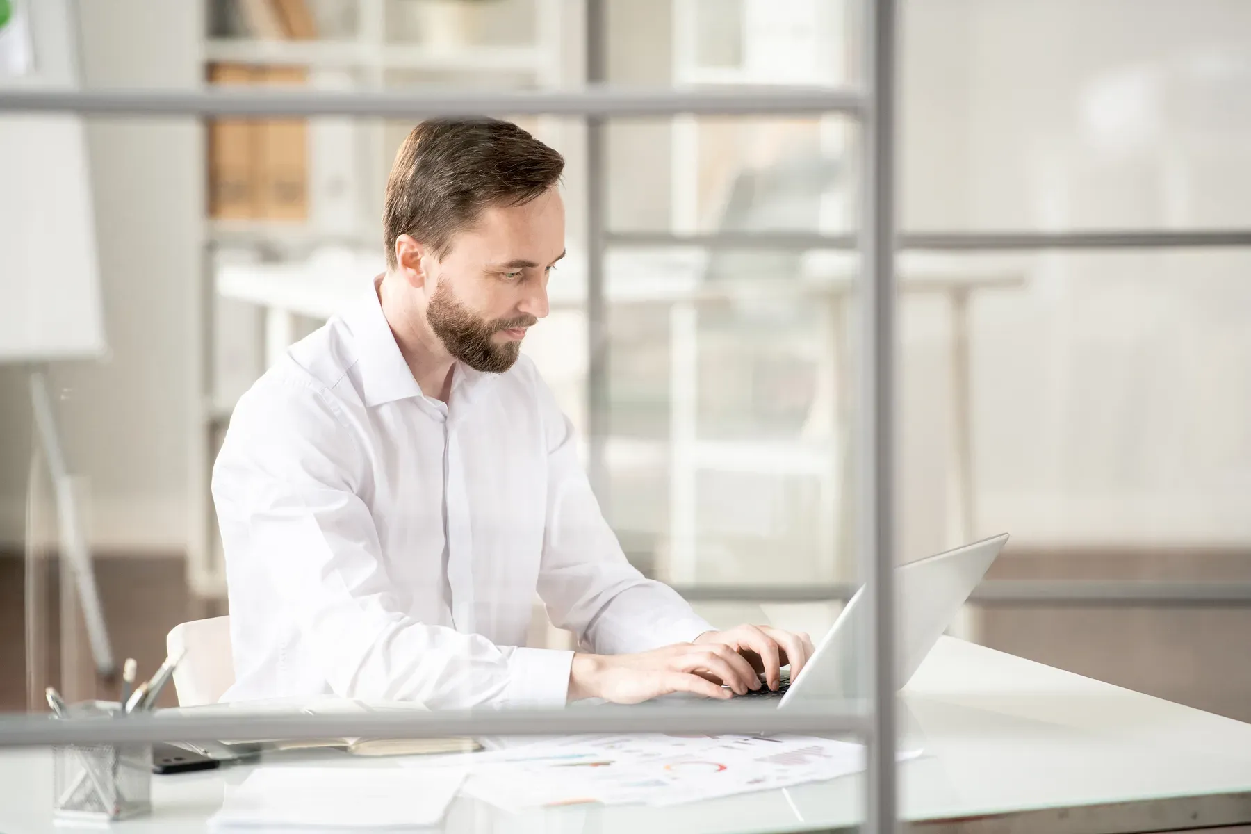 A professional working at a laptop in a private office at Grand Water Offices.
